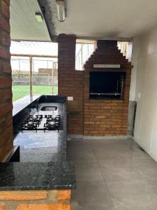 a kitchen with a stove and a wall with a tv at Chácara das Oliveiras in Campinas +3 photos