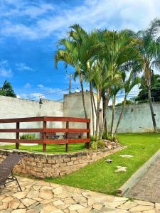 a wooden bench sitting in a park with palm trees at Chácara das Oliveiras in Campinas