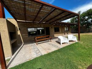 a patio with a wooden bench and chairs under a roof at Las Casitas y Los Duplex de Chacras de Coria in Chacras de Coria