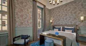 a bedroom with a bed with a desk and a chair at Hotel Taschenbergpalais Kempinski in Dresden