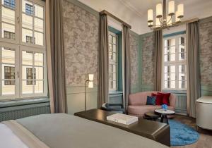 a bedroom with a bed and a chair and windows at Hotel Taschenbergpalais Kempinski in Dresden
