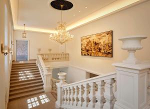 a staircase with a chandelier and a painting on the wall at Hotel Taschenbergpalais Kempinski in Dresden