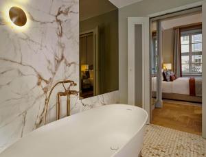 a bathroom with a white tub and a bedroom at Hotel Taschenbergpalais Kempinski in Dresden