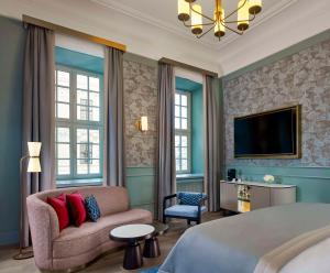a bedroom with a bed and a couch and a tv at Hotel Taschenbergpalais Kempinski in Dresden
