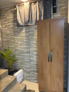 une armoire en bois dans une pièce avec un mur de briques dans l'établissement Kitnet Maria Bonita - Cabo frio, à Cabo Frio