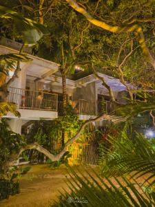 a large white building with a balcony and trees at Villa Mango Jeri in Jericoacoara