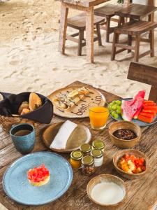 a wooden table with plates of food on a beach at Villa Mango Jeri in Jericoacoara