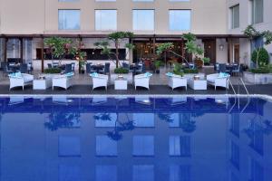 a hotel with tables and chairs next to a pool at Courtyard by Marriott Bengaluru Outer Ring Road in Bangalore