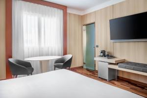 a hotel room with a bed and a flat screen tv at AC Hotel Badajoz by Marriott in Badajoz