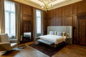 a bedroom with a bed and a chair and a chandelier at The Marmorosch Bucharest, Autograph Collection in Bucharest