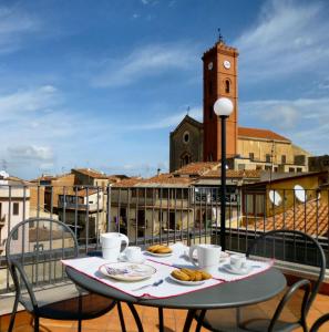 una mesa con comida en un balcón con una torre de reloj en Case Spazioscena - Polimnia, en Castelbuono