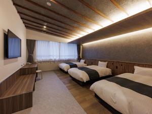 una camera d'albergo con tre letti e una televisione di 南紀月の瀬温泉ぼたん荘 a Takaike