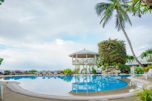 a resort pool with a gazebo and palm trees at Paras Beach Resort - Camiguin in Mambajao