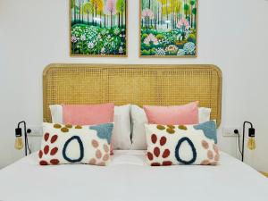 a bed with pink and white pillows and paintings at LOFT 1 - Space & Conform Close To Center in Valencia