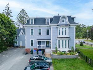 a large blue house with cars parked in a parking lot at 2-Bedroom Apartment, Historic Carriage House in Manchester