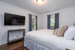 a bedroom with a white bed with a flat screen tv at 2-Bedroom Apartment, Historic Carriage House in Manchester