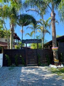 un cancello con un cartello di fronte a una recinzione con palme di Hospedaria aconchego 5 a Garopaba