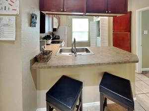 a kitchen with a sink and two bar stools at Beach Club Condo in Padre Island