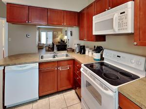 a kitchen with white appliances and wooden cabinets at Beach Club Condo in Padre Island