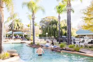 a man standing in the water in a pool with palm trees at Murray Downs Resort in Swan Hill
