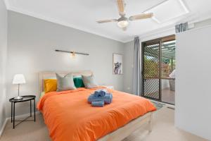 ein Schlafzimmer mit einem orangenen Bett mit zwei Teddybären darauf in der Unterkunft Cozy Lake Escape near Parliament, Embassies, Golf Club in Yarralumla