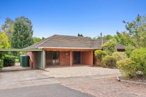 ein Backsteinhaus mit einer Einfahrt davor in der Unterkunft Cozy Lake Escape near Parliament, Embassies, Golf Club in Yarralumla
