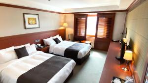 a hotel room with two beds and a television at Commodore Hotel Gyeongju in Gyeongju