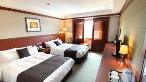 a hotel room with two beds and a television at Commodore Hotel Gyeongju in Gyeongju