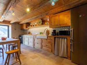 a kitchen with wooden cabinets and a table and a refrigerator at Maison de village 8 personnes à Loudervielle avec Wifi - FR-1-695-71 in Loudenvielle