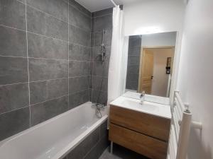 ein Badezimmer mit Badewanne, Waschbecken und Spiegel in der Unterkunft Appartement neuf 3 pièces, vue piste, parking couvert - FR-1-291-1026 in Valmorel