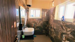une salle de bain avec un lavabo et deux fenêtres dans l'établissement Pahadi Safaari Cottage Mukteshwar, à Mukteswar