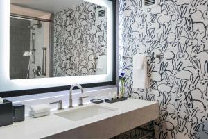a bathroom with a sink and a black and white wallpaper at The Lindy Renaissance Charleston Hotel in Charleston +29 photos