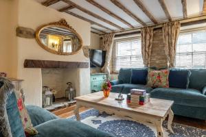 a living room with a blue couch and a table at Eilmers Cottage - Beautiful 4BD in Malmesbury! in Malmesbury