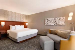 a hotel room with a bed and a couch at Courtyard by Marriott Bloomington Normal in Bloomington +16 photos