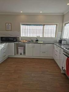 una cucina con mobili bianchi e una grande finestra di Glenview Holiday Park a Tokoroa