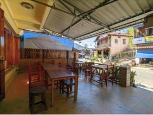 a restaurant with wooden tables and chairs and a patio at Thip Phavanh Guesthouse in Pakbeng