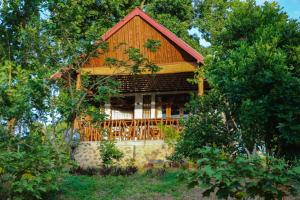 a log cabin with a porch in the woods at Warahana Riverside Cottage Udawalawa in Udawalawe