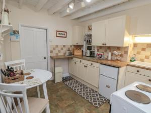 a kitchen with white cabinets and a table and chairs at 31 Outgang Road in Pickering +13 photos