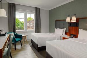 a hotel room with two beds and a desk at Courtyard by Marriott Hamburg Airport in Hamburg