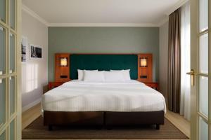 a bedroom with a large bed with a green headboard at Courtyard by Marriott Hamburg Airport in Hamburg