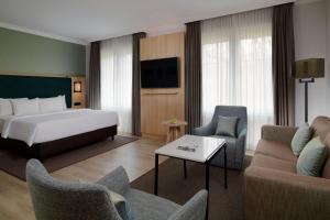 a hotel room with a bed and a couch and chairs at Courtyard by Marriott Hamburg Airport in Hamburg