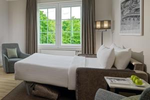 a hotel room with a bed and a couch at Courtyard by Marriott Hamburg Airport in Hamburg