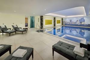 a swimming pool in a room with chairs and a couch at Courtyard by Marriott Hamburg Airport in Hamburg