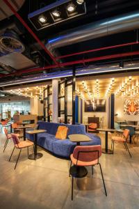 a room with a blue couch and tables and chairs at Aloft Brussels Schuman in Brussels
