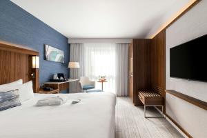 a hotel room with a bed and a flat screen tv at Courtyard by Marriott Glasgow Airport in Paisley