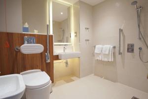 a bathroom with a toilet and a sink and a shower at Courtyard by Marriott Glasgow Airport in Paisley +37 photos