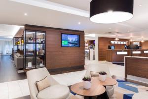 a lobby with two chairs and a tv on a wall at Courtyard by Marriott Glasgow Airport in Paisley