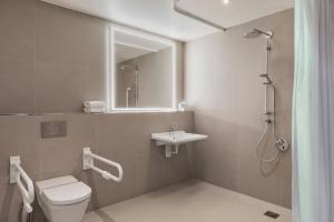 a bathroom with a toilet and a sink and a shower at Courtyard by Marriott Freiburg in Freiburg im Breisgau +30 photos