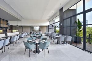 a restaurant with tables and chairs and large windows at Fairfield by Marriott Vadodara in Vadodara