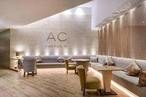 a hotel lobby with a couch and tables and chairs at AC Hotel Genova by Marriott in Genoa